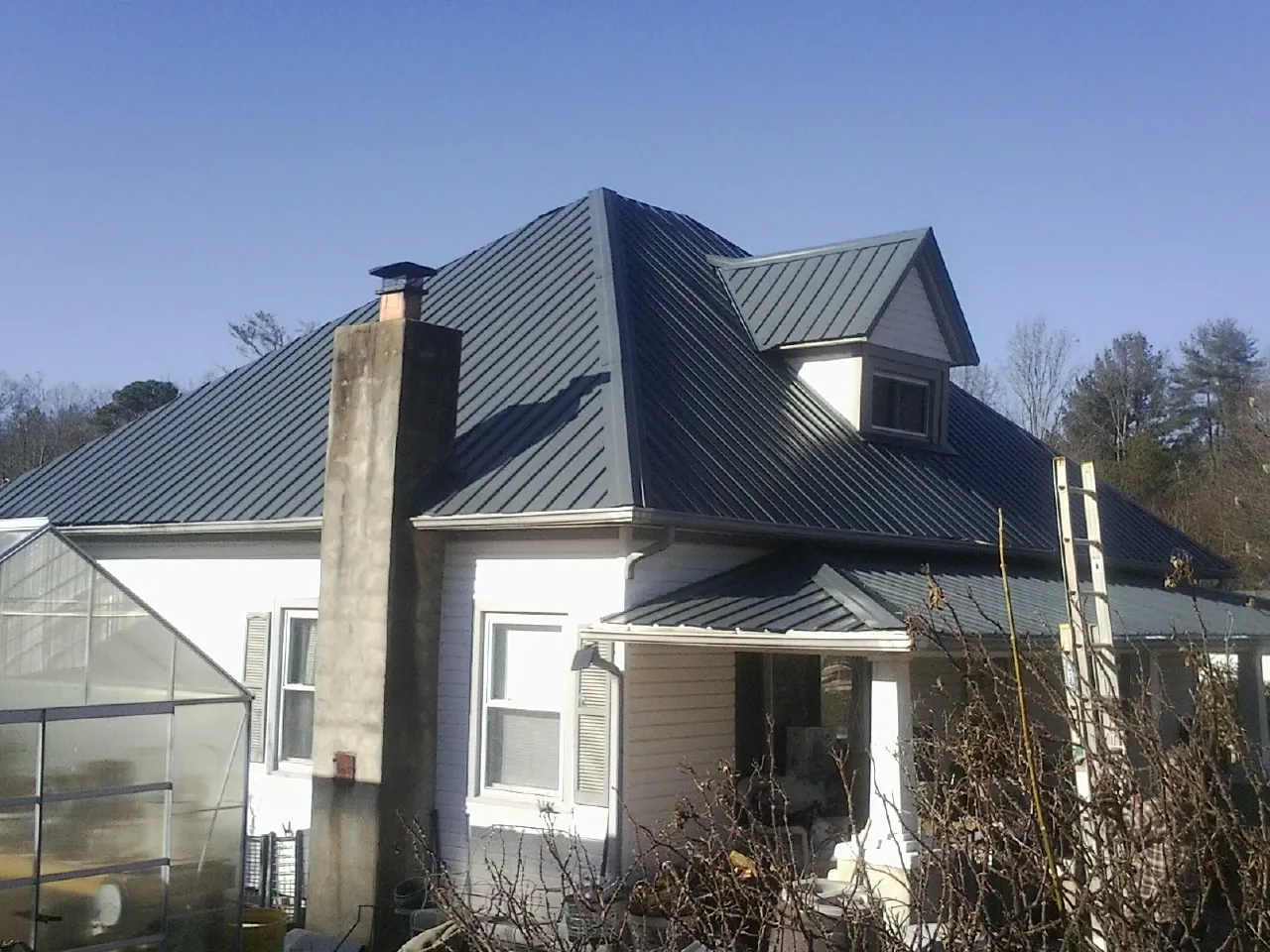 Dark blue standing seam metal roof on a white farmhouse with dormer — Slate & Tile Roof Repair by Roofing Brothers in Glengary