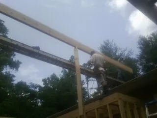 Carpenter setting a ridge beam over a new addition frame — Ice Dam Removal by Roofing Brothers in Glengary