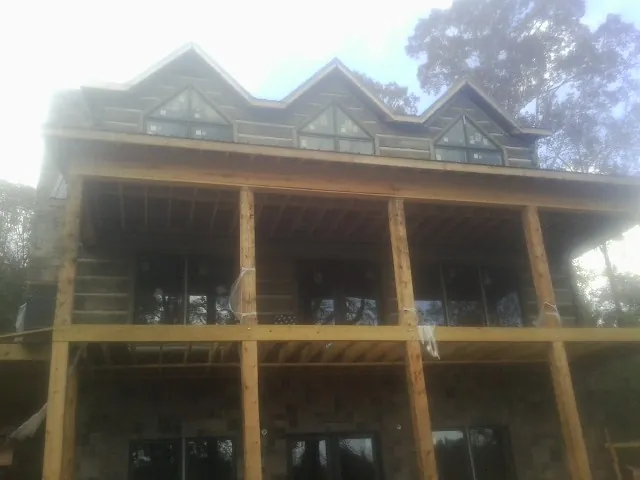 Dormers and porch framing on a large log home under construction — Roof Coating work by our crew in Glengary