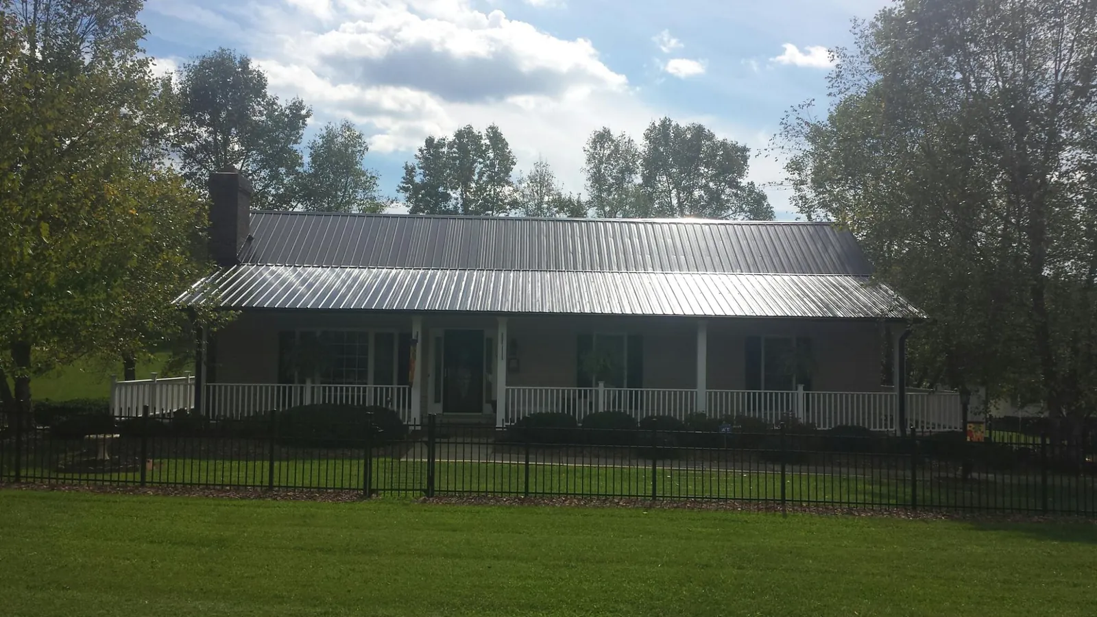 Gray metal roof on a brick ranch with a full width front porch — Gutter Guard Installation work by our crew in Glengary