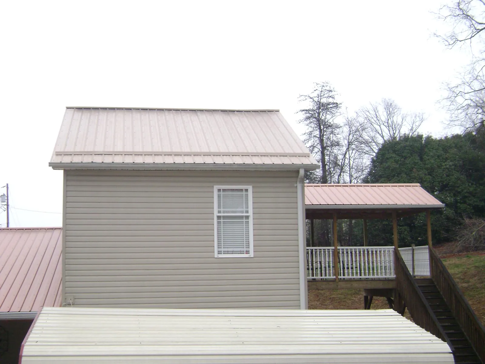 Tan metal roofs on a two story addition and attached porch, from a Roof Replacement job in Glengary
